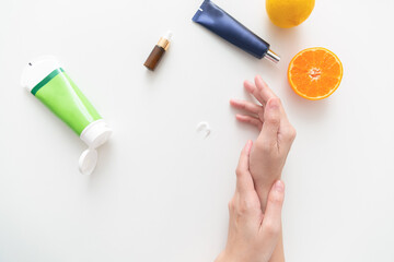 Woman hand holding cream tube and applying moisturizer cream on her beautiful hands. top view