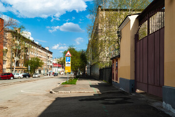 Obraz premium Free street. Street with roadway and sidewalks, on the sides of apartment buildings with parked cars. Clear sunny day, blue sky with white clouds