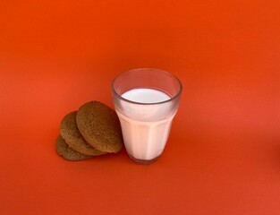 Glass of milk with brown oatmeal cookies on a beard background