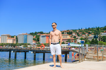 Man with muscular body and strong torso in sunglasses at the sea