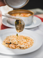 Plate and ladle with Portuguese traditional dish Arroz de Marisco or seafood rice on table in local cafe in Lisbon, Portugal. Portuguese national cuisine