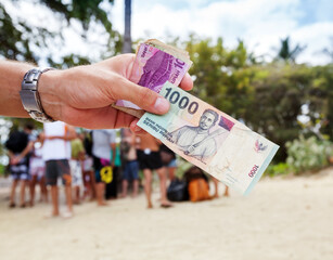 Paper banknote in thousand Indonesian rupiahs in the hand of man from a tourist on the background...