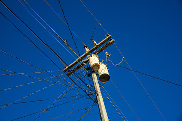 Electric wires and pillar on blue sky background. Tangle of electrical wires. Electric pillar with...