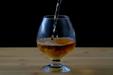 Filling a glass with fresh apple juice on a wooden surface with a black background