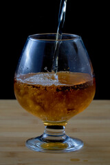 Filling a glass with fresh apple juice on a wooden surface with a black background