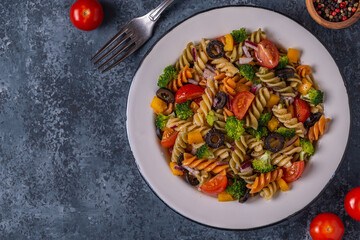 Pasta salad with tomato, broccoli, black olives.