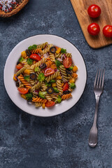 Pasta salad with tomato, broccoli, black olives.