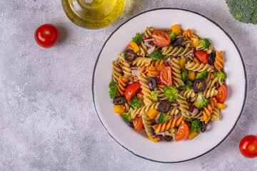 Pasta salad with tomato, broccoli, black olives.