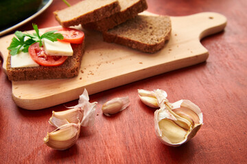 healthy food - fresh bread and feta cheese on a wooden background, tomatoes, greens and vegetables