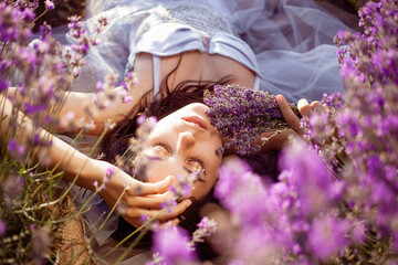 A beautiful girl in a lavender field. Beauty, beautiful makeup, lavender perfume, fashion. A professional model for advertising, an empty space for text. A woman holds a bouquet of flowers