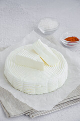 Homemade fresh soft cheese brynza or feta with chilli and sea salt on a light background. Vertical, copy space.