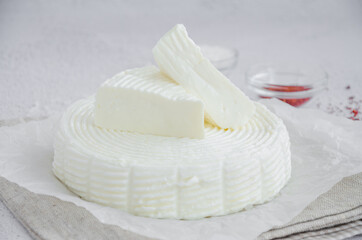 Homemade fresh soft cheese brynza or feta with chilli and sea salt on a light background. Horizontal, copy space.