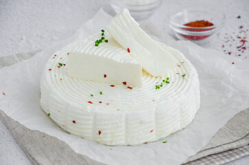 Homemade fresh soft cheese brynza or feta with chilli and sea salt on a light background. Horizontal, copy space.