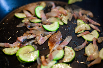 Preparazione per spaghetti con zucchini e pancetta saltati in padella.