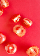 ripe shiny whole tomatoes, half and a quarter on a red background. Concept red on red.