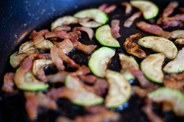 Preparazione per spaghetti con zucchini e pancetta saltati in padella.