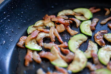 Preparazione per spaghetti con zucchini e pancetta saltati in padella.