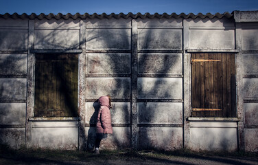 petite fille en blouson rose devant une maison abandonnée