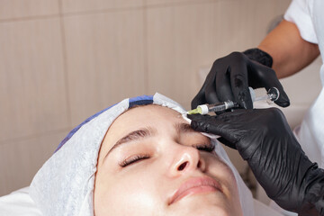 The beautician performs the procedure of mesotherapy in the beauty salon. Helps deliver vitamins,...