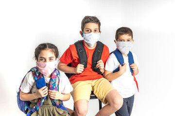 Three kids with backpacks and face masks