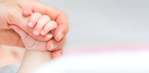 Close-up of baby's hand holding mother's finger with tenderness with copy space