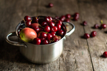 Sweet cherries and nectarines lie in a metal pan on a wooden table. Conservation for the winter.