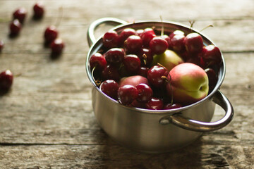 Sweet cherries and nectarines lie in a metal pan on a wooden table. Conservation for the winter.