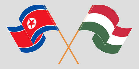 Crossed and waving flags of North Korea and Hungary