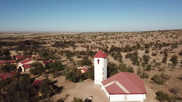 4K aerial drone video of Africa savanna hills and plains, tiny settlement Baimgartsbrunn and small white stone church west of Windhoek in central highland Khomas Hochland of Namibia, southern Africa