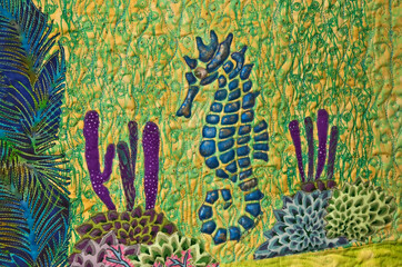 This is a closeup of a section of a sea horse quilt with shades of blues and greens in horizontal format with no people.
