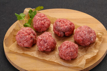 Raw meatball over wooden background