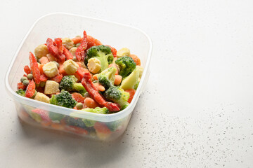 Frozen food colorful vegetables on plastic container on white background Close up. Copy space.