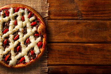Brazilian pizza with meat, tomato and cream cheese. top view on wood background, close up. Traditional Brazilian Pizza