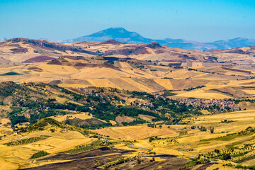 A patchwork of fields in the Madonie Mountains, Sicily with Mount Etna in the far distance during summertime