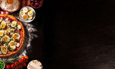 Traditional Portuguese Pizza with egg, olive, palm heart and pea. Top view on black concrete background, close up. Traditional Brazilian Pizza