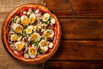 Traditional Portuguese Pizza with egg, olive, palm heart and pea. Top view on wood background, close up. Traditional Brazilian Pizza