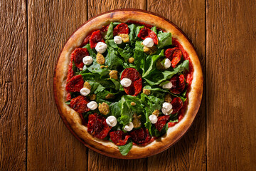 Brazilian pizza with dried tomato, arugula and mustard. Top view on wood background, close up. Traditional Brazilian Pizza