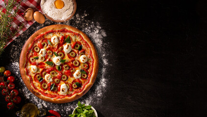 Obraz na płótnie Canvas Brazilian pizza with tomato, cream cheese, olive and basil. Top view on black concrete background, close up. Traditional Brazilian Pizza