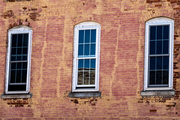 Three old windows set in an old red brick wall