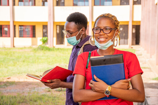 female african student on campus, smiling, another student behind her