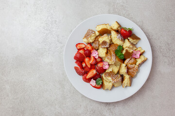 Kaiserschmarren or Kaiserschmarrn, traditional Austrian or German sweet pancake dessert, with berry, strawberry jam or rote grutze and vanilla pudding sauce. Top view. Copy space.