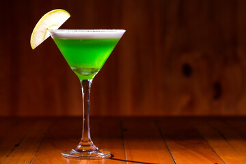 Apple Martini mixed drink with apple slice garnish on wood background