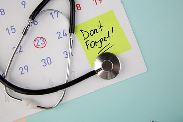 Reminder written on a sticky note on a calendar to visit a doctor.