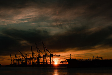 Fototapeta na wymiar A large ship and container cranes at sunset