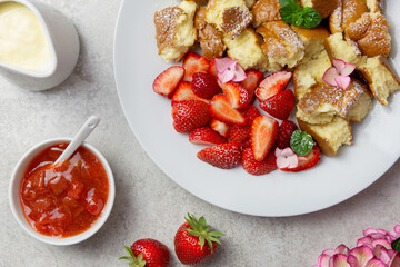 Kaiserschmarren or Kaiserschmarrn, traditional Austrian or German sweet pancake dessert, with berry, strawberry jam or rote grutze and vanilla pudding sauce. Top view.