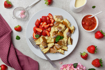 Kaiserschmarren or Kaiserschmarrn, traditional Austrian or German sweet pancake dessert, with berry, strawberry jam or rote grutze and vanilla pudding sauce. Top view.