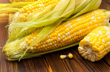 Fresh corn on cobs on rustic wooden table, closeup