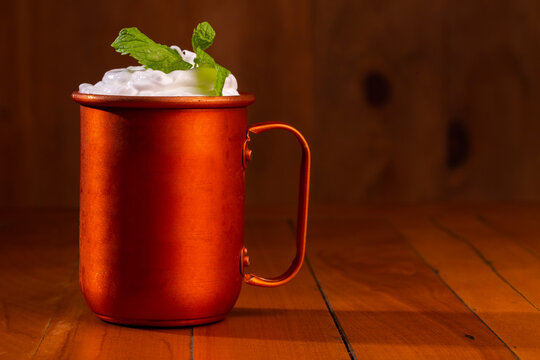Moscow mules cocktail in copper mugs with green mint leaves. Beautiful and delicius Moscow Mule drinks served on a wooden table