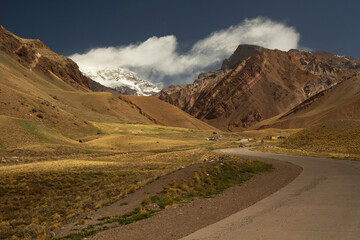 Path across the golden meadow that leads to mountain Aconcagua, highest peak in America. 