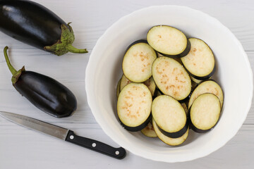 Eggplant, sliced with slices, are in bowl on a white background, top view, Closeup